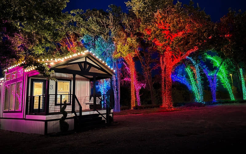 Casita 3 at night, its roofline lit, under trees wrapped in red, pink, blue and green lights
