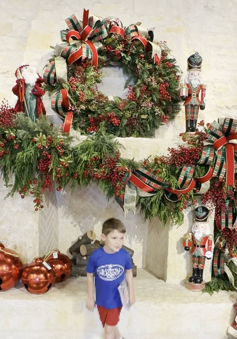 The stone fireplace at the Plano store dressed with a plaid-ribbon wreath, berry garland, nutcrackers and red bells