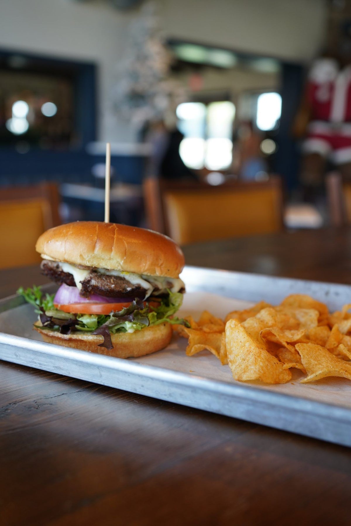 A Wagyu burger on a brioche bun with kettle chips on a sheet tray