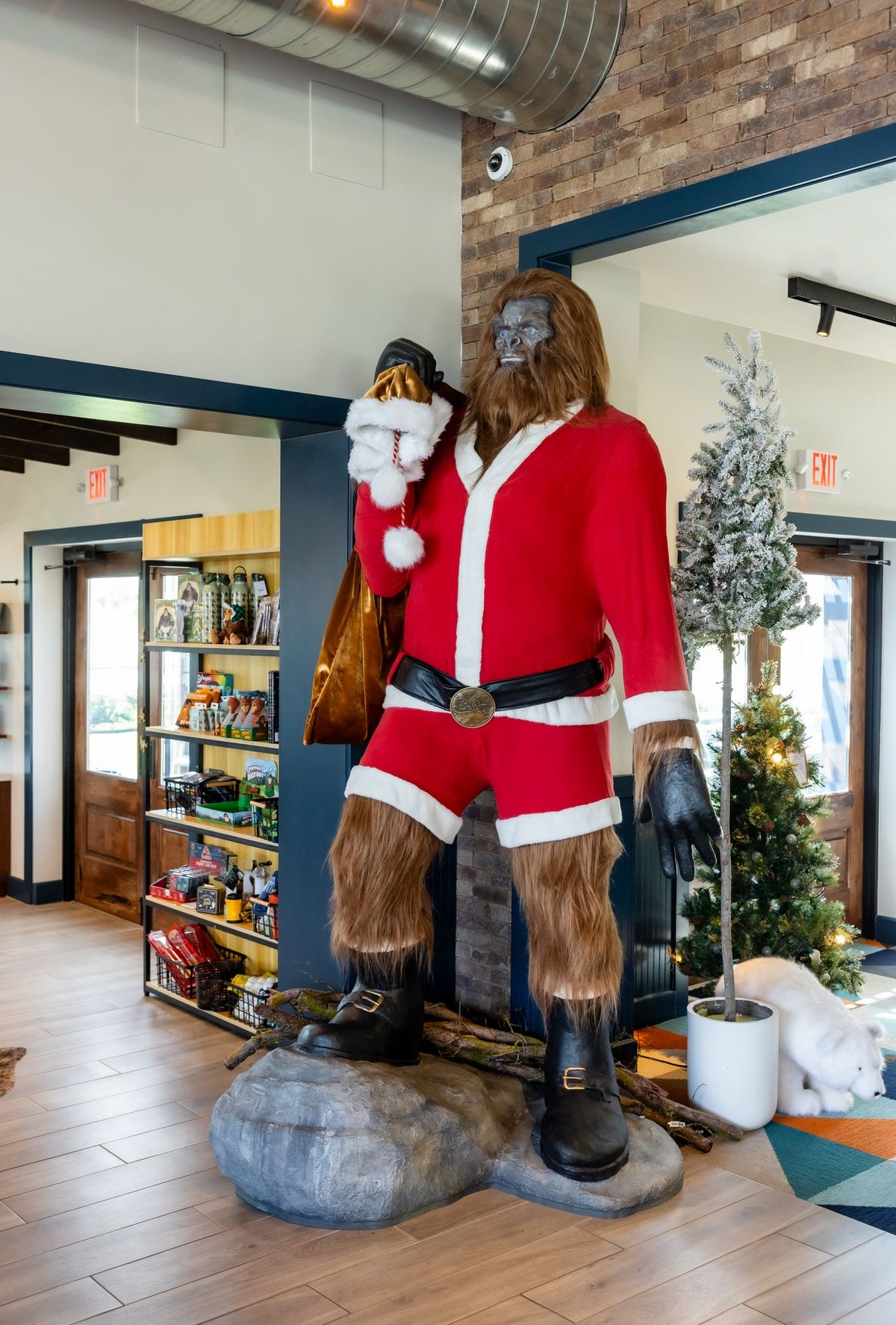 A full-length Sasquatch statue in a Santa suit, holding a sack of gifts