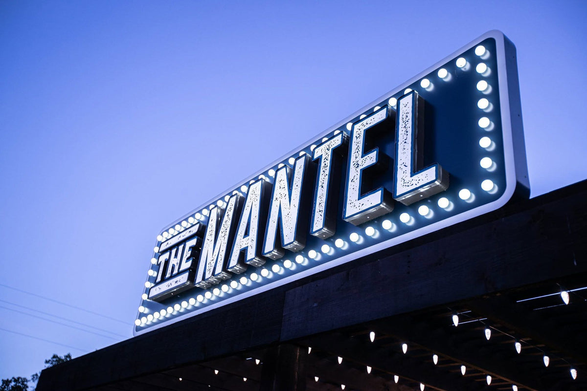 The Mantel’s marquee sign, lit with bulbs at blue hour